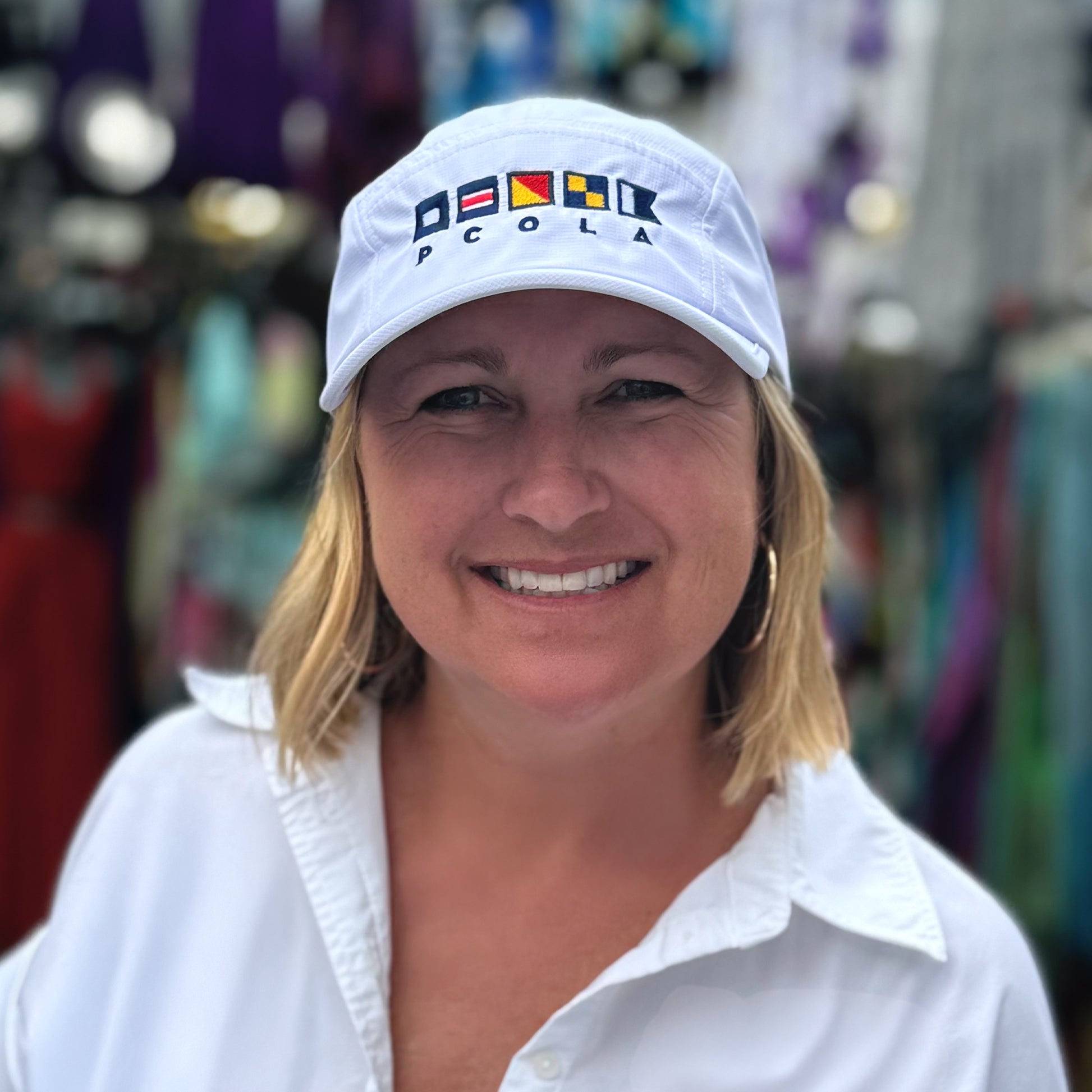 Performance white hat with signal flags spelling 'PCOLA,' a nod to coastal Pensacola, Florida.